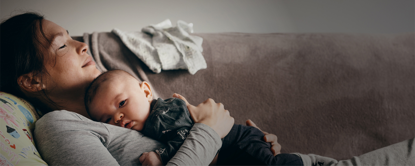 Woman with baby resting on couch.